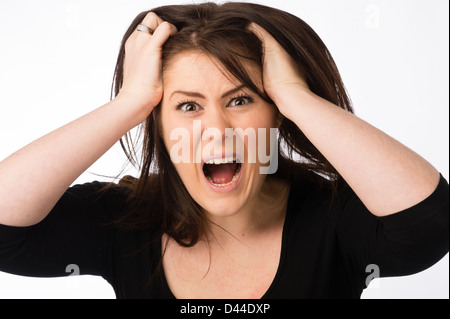 A young angry shouting woman, tearing her brown hair out , UK Stock Photo