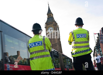 London Police officers wearing helmets & high visibility jackets, Westminster street duty back view. Westminster Bridge Houses of Parliament London UK Stock Photo