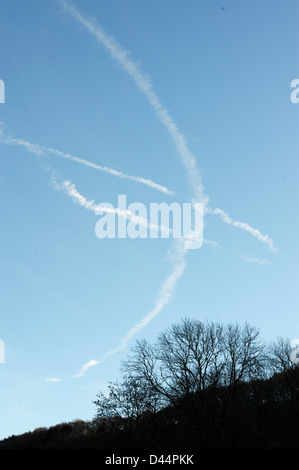 Aircraft vapour trails form a bird like pattern over woodland, Wales, UK Stock Photo