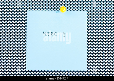 Postit note saying Merci arranged on black and white background Stock Photo