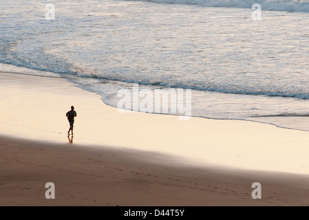 man jogging along the beach at sunset in Fuerteventura Stock Photo