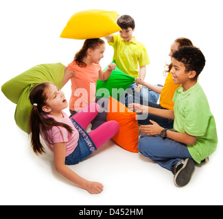 Five teen kids fighting with pillows, laughing and having fun, isolated on white Stock Photo