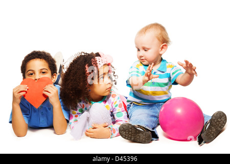 Three little kids black boy and girl and Caucasian child playing together Stock Photo