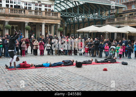 Group of people watching a street entertainer doing hand stands at Covent Garden London UK Stock Photo