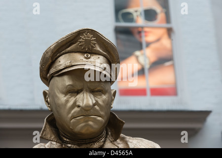 Gold painted male mime artist by a street advertisement Covent Garden London UK Stock Photo