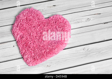 A large pink heart rug set on a white aged wooden floor Stock Photo