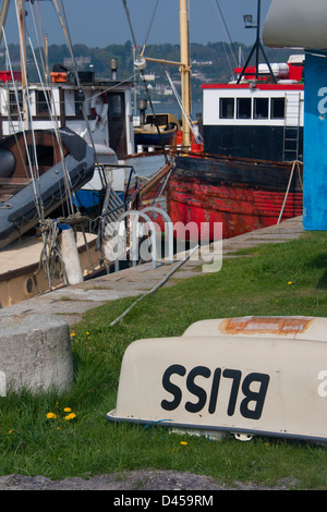 Porth Penrhyn harbour in Bangor Gwynedd Wales UK Upturned boat named 'Bliss' with fishing boats along quayside in background Stock Photo