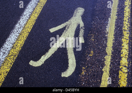 Quirky icon of pedestrian painted on tarmac road surface between yellow No Parking lines to show where people on foot go Stock Photo