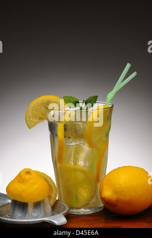 Closeup of a cold glass of fresh squeezed lemonade on a wood table and a light to dark gray background. Stock Photo