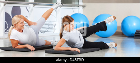 Two elderly women exercising together in fitness center on gym mats Stock Photo