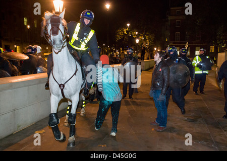Mounted Policeman in full riot gear dragging a protesting student by his clothes on Whitehall at night, Day X3 Student Demonstration, London, England Stock Photo