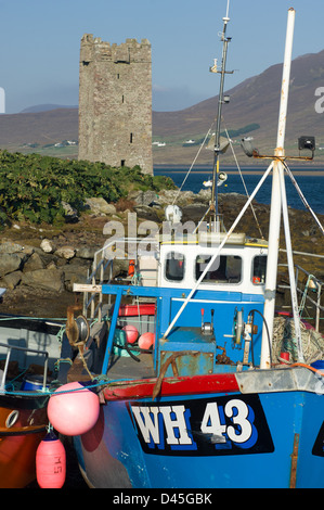 Small fishing boats moored in front of Grace O'Malley's Tower (Kildavnet Castle) a 16th century tower on Achill Island, Westport, County Mayo, Ireland Stock Photo