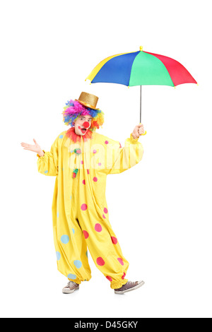 Full length portrait of a cheerful clown holding a colorful umbrella isolated on white background Stock Photo