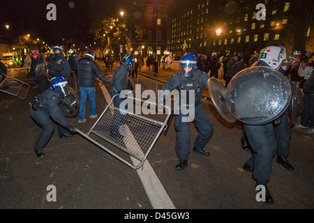 Police in full riot gear dragging away a crowd control barrier on Whitehall at night, Day X3 Student Demonstration, London, England Stock Photo