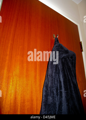 Black toweling dressing gown hanging on back of bedroom door Stock Photo