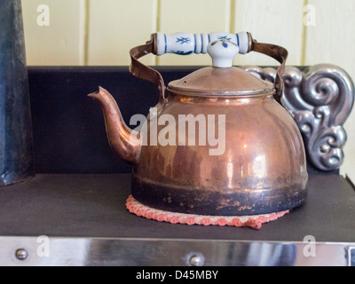 Copper Kettle. An old antique kettle on an old stove. Stock Photo