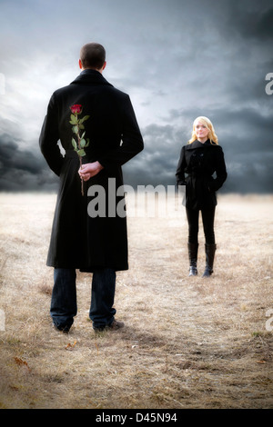 a man hides a red rose to surprise his girlfriend Stock Photo