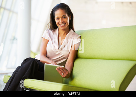 Businesswoman Sitting In Modern Office Using Digital Tablet Stock Photo