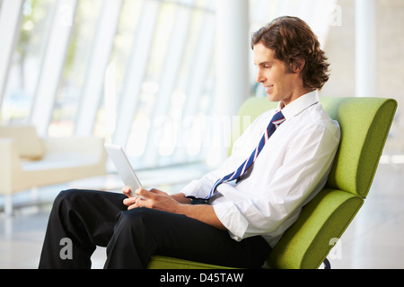 Businessman Sitting In Modern Office Using Digital Tablet Stock Photo