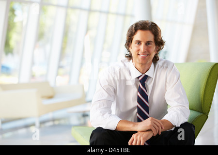 Businessman Sitting On Sofa In Modern Office Stock Photo