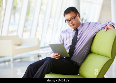 Businessman Sitting In Modern Office Using Digital Tablet Stock Photo
