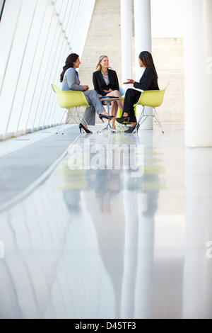 Three Businesswomen Meeting Around Table In Modern Office Stock Photo
