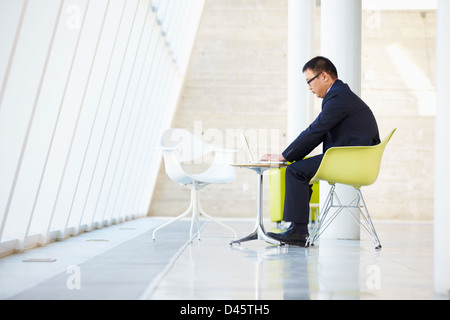 Businessman Working On Laptop At Table In Modern Office Stock Photo