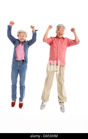 Studio Shot Of Chinese Senior Couple Jumping In Air Stock Photo