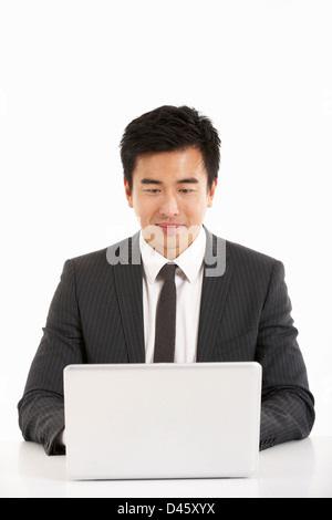 Studio Shot Of Chinese Businessman Working On Laptop Stock Photo