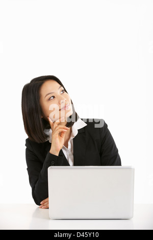 Studio Shot Of Thoughtful Chinese Businesswoman Working On Laptop Stock Photo