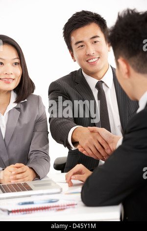 Studio Shot Of Two Chinese Businessmen Shaking Hands During Meeting Stock Photo