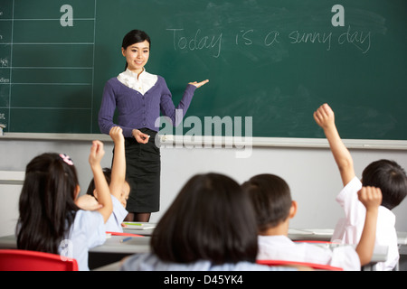 Teacher Standing By Blackboard In Chinese School Classroom Stock Photo