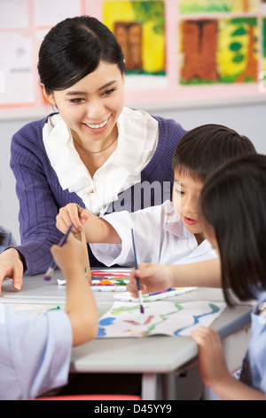 Teacher Helping Students During Art Class In Chinese School Classroom ...
