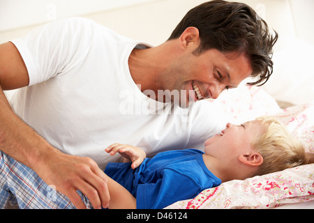 Father And Son Relaxing Together In Bed Stock Photo