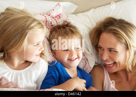 Mother And Children Relaxing Together In Bed Stock Photo