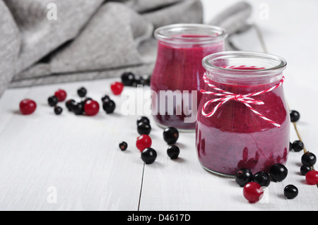 Cranberry and black currant smoothie in glass jars on a white wooden background Stock Photo