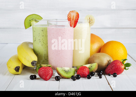 Fruit smoothies with black currant, strawberry, kiwi, orange and banana on white wooden background Stock Photo