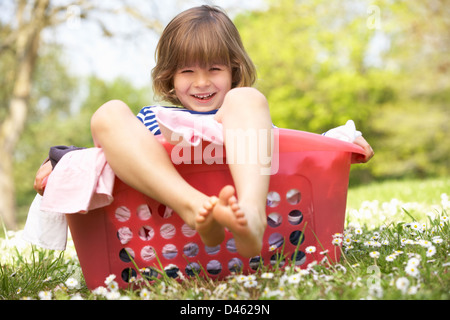 Young Boy Sitting In Laundry Basket Stock Photo