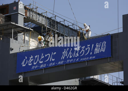 Fukushima, Japan. 6th March 2013. Workers wearing protective suits and masks are seen atop of foundation construction for storage of melted fuel rods next to the No.4 reactor at Tokyo Electric Power Co. (TEPCO)'s tsunami-crippled Fukushima Daiichi nuclear power plant in Fukushima prefectureahead of the second-year of anniversary of the the March 11, 2011 tsunami and earthquake. The banner reading ''Unite the Heart, Gambaro! Fukushima (Go! Fukushima)'. Credit:  ZUMA Press, Inc. / Alamy Live News Stock Photo