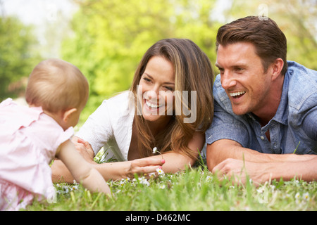 Parents With Baby Girl Sitting In Field Of Summer Flowers Stock Photo