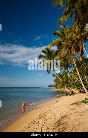 A woman enjoys a leisurely walk on a secluded beach in Las Terrenas. Stock Photo