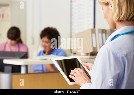 Female Doctor Using Digital Tablet At Nurses Station Stock Photo