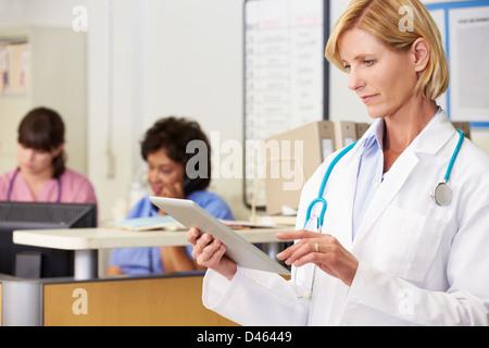 Female Doctor Using Digital Tablet At Nurses Station Stock Photo