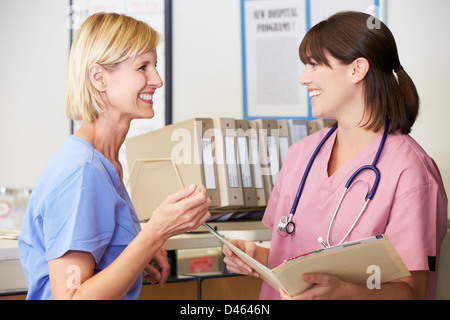 Nurse Reading Patient Notes At Nurses Station Stock Photo
