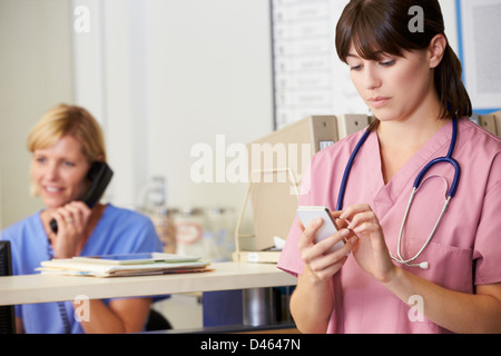 Two Nurses Discussing Patient Notes At Nurses Station Stock Photo