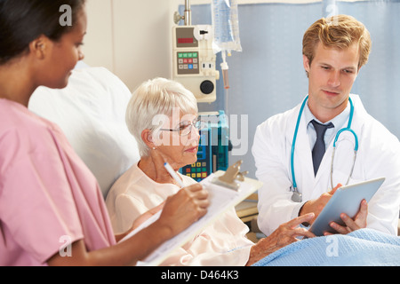 Doctor Using Digital Tablet In Consultation With Senior Female Patient In Bed Stock Photo