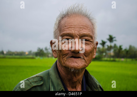 Very old Vietnamese man standing in a rice paddy. Stock Photo