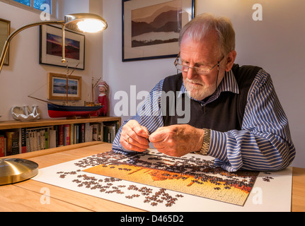 Retired man, OAP, with jigsaw puzzle at home. UK Stock Photo