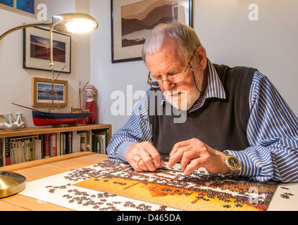 Retired man, OAP, with jigsaw puzzle at home. UK Stock Photo