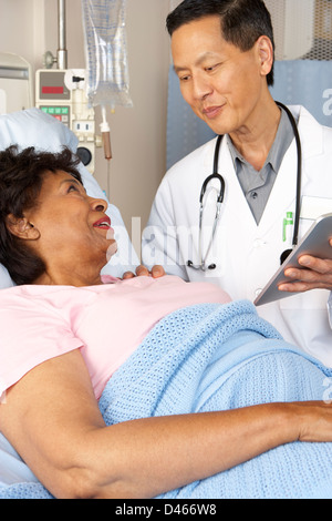 Doctor Using Digital Tablet Talking With Senior Patient Stock Photo